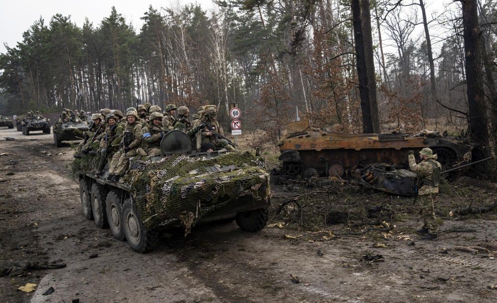 Ukrainian soldiers pass on top of armored vehicles next to a destroyed Russian tank in the outskirts of Kyiv, Ukraine, Thursday, March 31, 2022. (AP PhotoRodrigo Abd)